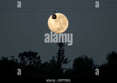 Santiago, Metropolitana, Cile. 28 Feb 2021. La luna piena di febbraio, chiamata Luna di neve, si pone dietro una funivia turistica a Santiago. Credit: Matias Basualdo/ZUMA Wire/Alamy Live News Foto Stock