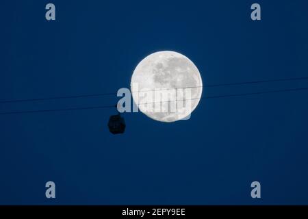 Santiago, Metropolitana, Cile. 28 Feb 2021. La luna piena di febbraio, chiamata Luna di neve, si pone dietro una funivia turistica a Santiago. Credit: Matias Basualdo/ZUMA Wire/Alamy Live News Foto Stock