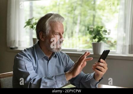 Il vecchio uomo dai capelli grigi ha messo a fuoco utilizzando l'app sullo smartphone Foto Stock