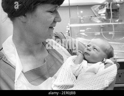 BAMBINO ABBANDONATO 'GEOFFREY' ALL'OSPEDALE DI ST MARY, NEWPORT, ISOLA DI WIGHT. TENENDOLO È L'OSTETRICA DEL PERSONALE, RUTH CHATER (35) DELL'UNITÀ SPECIALE DEL BAMBINO DI CURA. 1983. PIC MIKE WALKER, M. E Y. PORTSMOUTH. Foto Stock