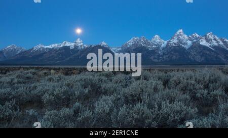 Luna ambientazione dietro le montagne Teton. Foto Stock