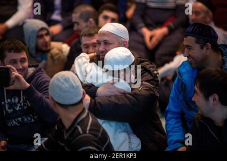 Un padre abbracca un bambino dopo che recita una surah dal libro santo musulmano del Corano al festival annuale del Corano nella moschea della cattedrale di Mosca, Russia Foto Stock