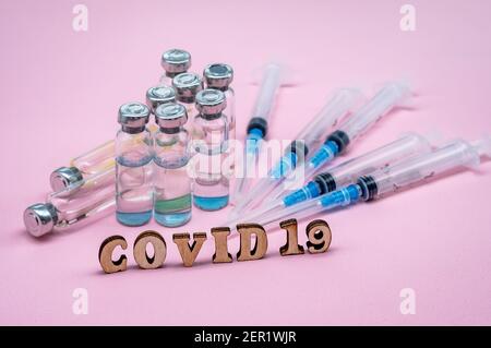 Prevenzione delle malattie stagionali. Fiale mediche e asiringi su sfondo rosa. Vaccinazione contro covid-19. Foto Stock
