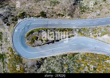 Vista dall'alto drone aereo immagine della strada asfaltata curva di 180 gradi circondata da scogliere sull'isola di Madeira, Portogallo. Concetto di trasporto di sicurezza. Foto Stock