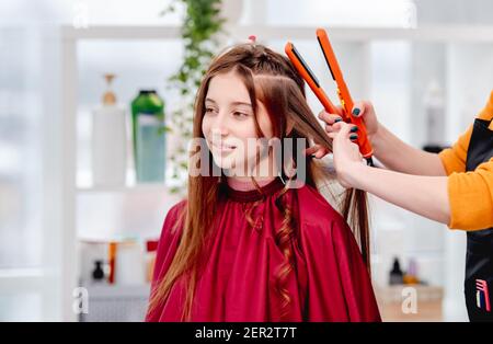 Il parrucchiere avvolge i ricci con un ferro da stiro Foto Stock