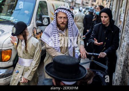 Gerusalemme, Israele. 28 Feb 2021. Persone ebree ultra ortodosse vestite in abiti tradizionali, prendetevi parte alle celebrazioni della festa ebraica di Purim nel quartiere Mea She'arim di Gerusalemme. Purim, chiamato anche Festival of Lots, è una festa ebraica simile a carnevale che commemora la salvezza del popolo ebraico da un complotto per massacrare tutti gli ebrei nell'antico impero persiano, come raccontato nel Libro di Esther. Credit: Ilia Yefimovich/dpa/Alamy Live News Foto Stock