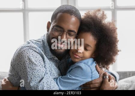 Ritratto di felice carina ragazza nera abbracciando il suo amato papà Foto Stock