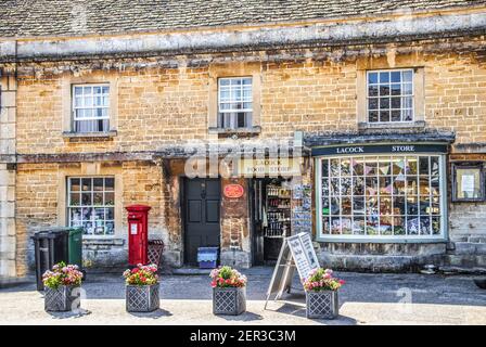 7-25-2019 Lacock UK - Negozio e ufficio postale del villaggio aperti Nella giornata di sole a Lacock UK con fiori davanti di edifici antichi con cartoline su scaffale Foto Stock