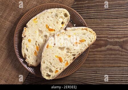 Due fette di pane di ciabatta con albicocca secca e semi di zucca in piastra su un tavolo di legno, vista dall'alto Foto Stock