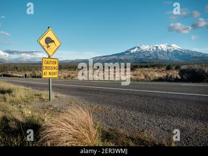 Cartello di passaggio Kiwi accanto al Monte Ruapehu innevato nel parco nazionale Tongariro della Nuova Zelanda. Foto Stock