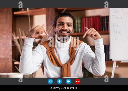 Insegnante sorridente che punta verso il basso mentre dà informazioni allo studente Foto Stock