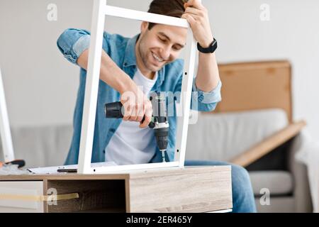 Assemblaggio di mobili per truciolare con un cacciavite a batteria a casa Foto Stock