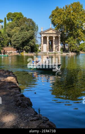 Italia, Roma, persone in barca a remi sul lago nei Giardini di Villa Borghese e Tempio di Asculapio Foto Stock