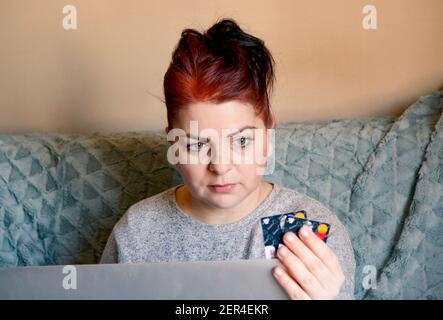 Donna dai capelli rossi che tiene le carte di credito e un giro in cima Foto Stock