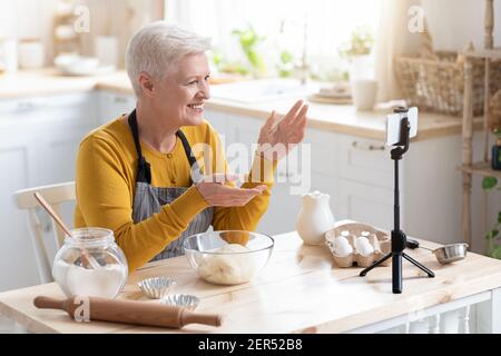 Anziana donna blogger cibo registrazione la sua cucina su smartphone Foto Stock