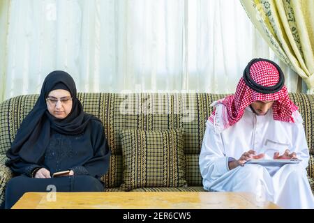 Coppia musulmana seduta accanto a ciascuno ma non guardando l'uno con l'altro Foto Stock