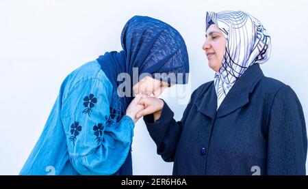 Ragazza musulmana araba che baciano le mani della madre per rispetto Foto Stock