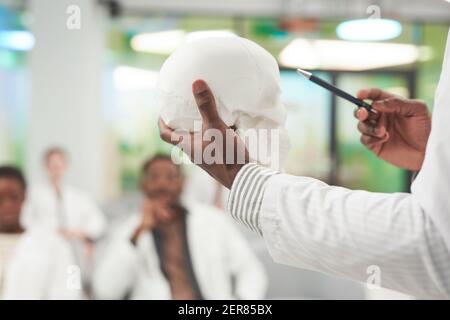 Primo piano dell'irriconoscibile modello di teschio dell'uomo afro-americano durante la lezione sulla medicina all'università o al centro di lavoro Foto Stock