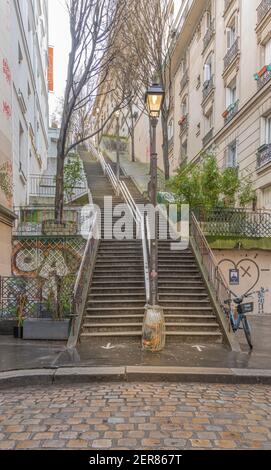 Parigi, Francia - 02 26 2021: Quartiere di Montmartre. Scala in pietra con lanterne illuminate Foto Stock