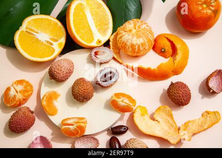 Gustosi litchi e arance arrangiate su tavola rosa Foto Stock