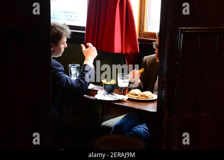 Due uomini che chiacchierano con una pinta e pranzano al pub della Guinea, Mayfair, Londra Foto Stock