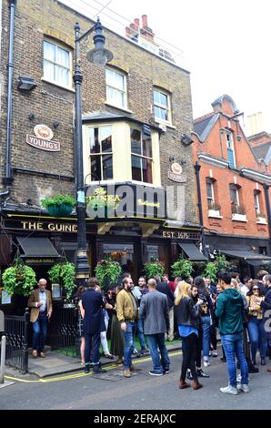 Persone che bevono fuori dal pub Guinea a Mayfair, Londra Foto Stock