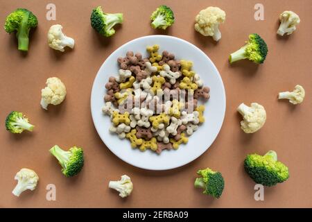 Crunchies vegetariano del cane su piatto e verdure su beige sfondo Foto Stock
