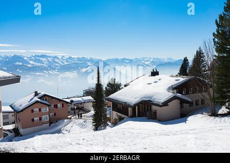 Vista panoramica unica dello skyline alpino del resort Rigi. Chalet innevati, cabine di alloggio in legno, alberghi, Alpi svizzere ghiacciate, cielo blu. Monte Rigi, Weggis, Luc Foto Stock