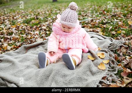 Bella bambina seduta sulla plaid. Bambini all'aperto. Adorabile bambina in abiti caldi al pic-nic in autunno parco il giorno di sole. Abbastanza piccolo gir Foto Stock