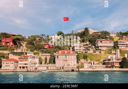 Vista dalle acque dello stretto di Bosforo su una zona residenziale collinare Blocchi di Kandilli quartiere con bandiera turca rossa in aumento Il cielo sopra Uskudar Foto Stock