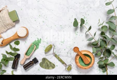 Cura naturale della pelle e aromaterapia con bottiglia di olio essenziale di eucalipto, sale da bagno, rullo di giada di bellezza, gua sha su sfondo marmoreo. Spa, wellness, m Foto Stock
