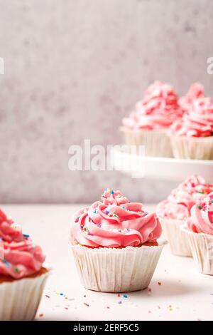 Cupcake alla vaniglia rosa classica con crema al burro di vaniglia e spolverare. Foto Stock