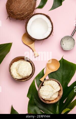 Creative laici piatta con gelato al cocco e piante tropicali su sfondo rosa Foto Stock