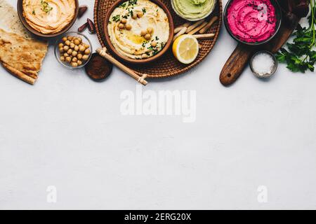 Piatto-lay di vari hummus di tuffi vegetariani. Diversi tipi di cadute. Hummus tradizionale, hummus alle erbe, hummus alle barbabietole e humus alle lenticchie Foto Stock