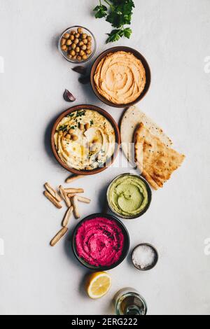 Piatto-lay di vari hummus di tuffi vegetariani. Diversi tipi di cadute. Hummus tradizionale, hummus alle erbe, hummus alle barbabietole e humus alle lenticchie Foto Stock