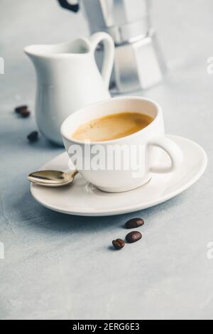 Composizione del caffè sul cemento bianco sullo sfondo. Caffè espresso in tazza bianca con latte e caffè. Concetto di colazione Foto Stock
