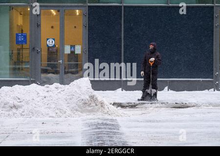 Mosca. Russia. 12 febbraio 2021. Un operaio di servizio tinge la neve con una pala su una strada della città durante una nevicata pesante in una giornata invernale. Eliminazione o Foto Stock