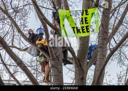 York Gardens, Londra, Regno Unito. 28th febbraio 2021. L'attivista ambientale Marcus Decker, 32 anni, parla con le persone riunite sotto un albero di pioppo nero di 100 anni che dovrebbe essere abbattuto il 23rd febbraio 2021 da Taylor Wimpey Homes e dal Consiglio di Wandsworth. Il quartiere e gli attivisti "stanno rispettando gli alberi" con una cerimonia pacifica al tramonto "per mostrare sostegno alla natura e ai protettori degli alberi". Artisti, persone comuni e attivisti ringraziano ritualmente gli oltre 124 alberi che si sono abbattuti per un progetto semi-privato di “rigenerazione”. Sabrina Merolla / Alamy Foto Stock