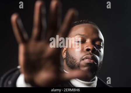 Uomo nero serio che ti dice di fermarti con una mano aperta. Foto Stock