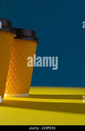 Tazza di carta a coste gialle con coperchio in plastica per bevande da asporto nei fast food. Una tazza di caffè, cacao, tè da un caffè di strada. Posto per voi Foto Stock