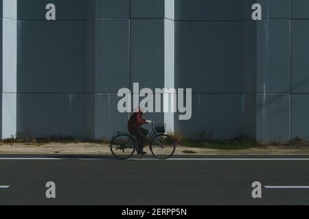 Un uomo che cavalcava una bicicletta passa da una parete di mare il 22 novembre 2020 a Yamada città, Iwate, Giappone. Quasi 10 anni dopo il terremoto dell'M9 e lo tsunami devastante, Tohoku (Giappone del Nord Est) è protetto da un massiccio muro di mare. Dalla prefettura di Fukushima alla prefettura di Iwate, più di 300 km di barriera d'onda sono già finiti. Il muro è alto da 3 metri a 15 metri. 22 novembre 2020 Credit: Nicolas Datiche/AFLO/Alamy Live News Foto Stock