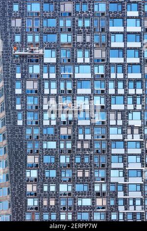 Frammento della facciata di un alto edificio in costruzione e il suo isolamento utilizzando argani e piattaforme mobili, il concetto di risparmio energetico Foto Stock