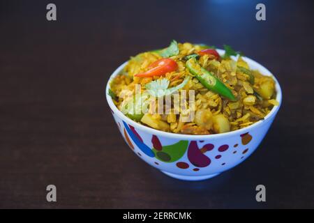 Riso fritto battuto con patate, cipolla, capsicum e peperoncino verde in stile indiano nepalese servito in una ciotola. Spuntini di riso appiattito, spuntini POHA Foto Stock