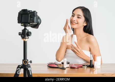 Giovane bella donna asiatica professionale di bellezza vlogger o blogger registrazione crea tutorial da condividere sui social media in bianco sfondo Foto Stock