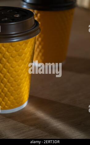 Tazza di carta a coste gialle con coperchio in plastica per bevande da asporto nei fast food. Una tazza di caffè, cacao, tè da un caffè di strada. Posto per voi Foto Stock