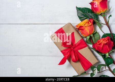 Belle rose rosse su sfondo bianco di legno. Composizione floreale festosa con scatole regalo di carta artigianale. San Valentino, giorno delle donne, giorno delle madri saluto Foto Stock