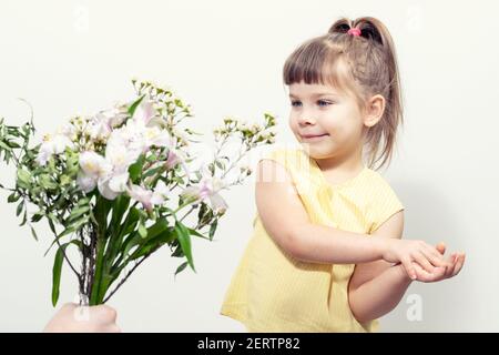 la mano di un uomo tiene fuori un bouquet di fiori bianchi ad una bambina carina Foto Stock