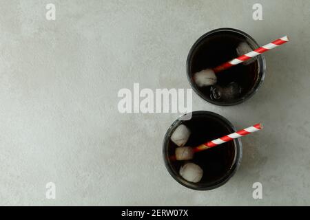 Bicchieri di cola con cubetti di ghiaccio e paglia su bianco sfondo testurizzato Foto Stock