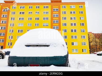 Parcheggio auto su lotti in case quartiere mentre la neve cade continuamente in inverno Foto Stock