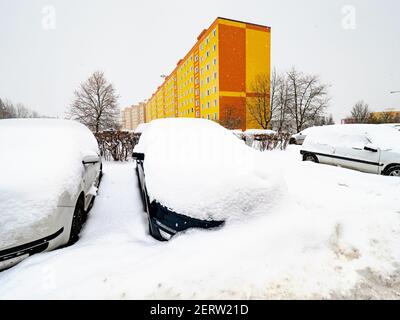 Parcheggio auto su lotti in case quartiere mentre la neve cade continuamente in inverno Foto Stock